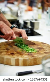 Food Lifestyle Photography Of A Caucasian Male Chef Chopping Herbs (ingredients Being Prepared For Cooking) With A Kitchen In The Background