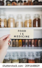 Food is Medicine text in front of tidy organised pantry with jars lined up on shelves, concept of dieting vs healthy nutrition and intuitive eating	