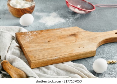 Food Mockup. Empty Wooden Board On Concrete Table With Pastry Ingredients. Wooden Board  With Flour, Eggs And Textile For Bakery Menu. Bakery Mockup. Pastry Composition With Empty Place