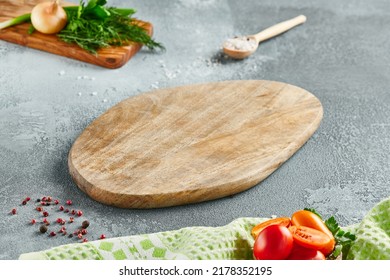 Food mockup. Empty wooden board on concrete table with cooking  ingredients. Wooden board  with spices, greens and tomatoes for menu. Food menu mockup. Cooking composition with empty place