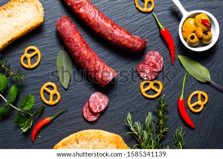 Food party background cured meat Saucisson french salami, olive, prezels and homemade bread on black slate stone 
