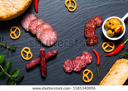 Food party background kind of cured meat Saucisson french salami, olive, prezels and homemade bread on black slate stone 