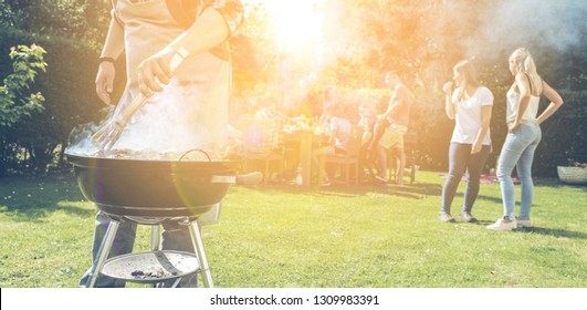 Food, people and family time concept - man cooking meat on barbecue grill at summer garden party