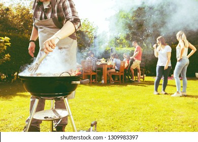 Food, people and family time concept - man cooking meat on barbecue grill at summer garden party - Powered by Shutterstock