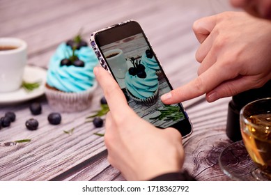 Fotografía de comida para el blog. Las manos femeninas disparan una foto de pastelitos en un smartphone. Blog de comida. Enfoque selectivo.