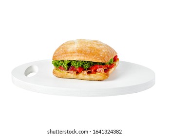 Food photography of a bread roll with salami, red capsicum (peppers) and lettuce on a white wooden board on a white background