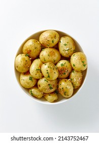 Food Photography Of Cooked Baked White Potatoes With Chopped Herbs And Maldon Sea Salt In A Bowl On A White Background.