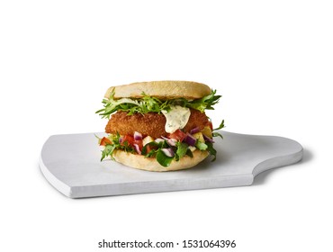 Food Photography Of Fish Burger With Mayo And Salad On A Wooden Serving Board On White Background