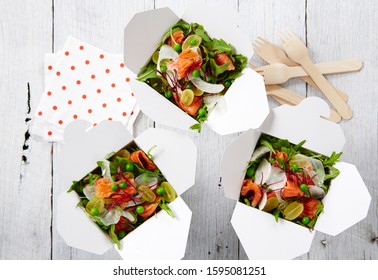 Food Photography Of Salad Boxes With Smoked Salmon, Rocket, Cherry Tomato And Pea Salad Shot Top Down On Timber Surface With Eco Cutlery