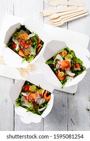 Food Photography Of Salad Boxes With Smoked Salmon, Rocket, Cherry Tomato And Pea Salad Shot Top Down On Timber Surface With Eco Cutlery