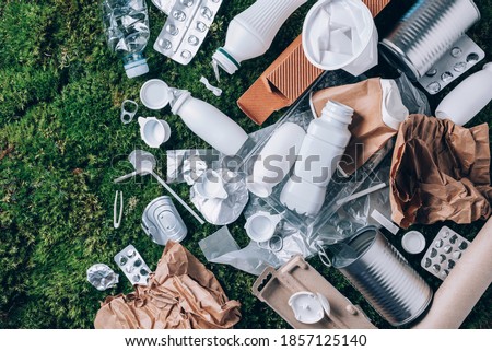 Food plastic packaging, trash on green moss background after picnic in forest. Top view. Copy space. Recycling plastic. Environmental pollution, ecology concept. Reuse garbage, recycle, plastic free