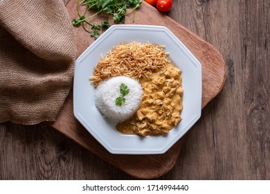 Food plate with meat stroganoff with rice and french fries. Wood background. Flat lay.