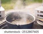 Food prepared in old cast iron outside. Romanian traditional food prepared at the cauldron on the open fire with wood, Christmas tradition. Preparing food on campfire in wild camping