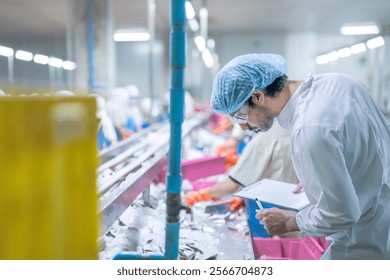 Food processing workers in protective gear, including lab coats, hair covers, and goggles, inspecting fish on ice in a factory setting, emphasizing hygiene, quality control, and safety standards. - Powered by Shutterstock