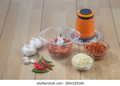 Food Processor With Chopped Chilli And Garlic On Wooden Table Background