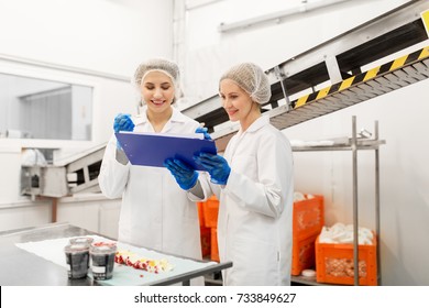 Food Production, Industry And People Concept - Happy Women Technologists With Clipboard Tasting Ice Cream Quality At Factory