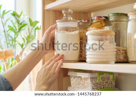 Food products in the kitchen storing ingredients in pantry. Woman taking jar of flour
