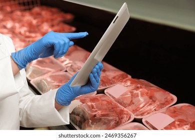 Food quality control specialist examining meat in supermarket, closeup - Powered by Shutterstock