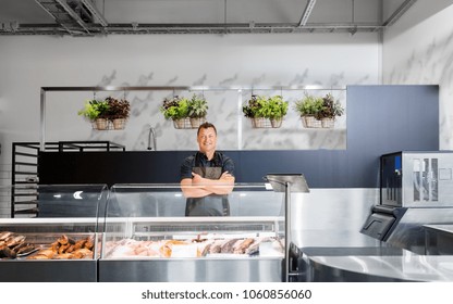 food sale, small business and people concept - male seller with seafood at fish shop fridge