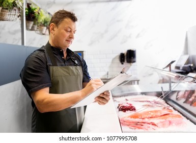 food sale, small business and people concept - male seller with clipboard selling seafood at fish shop - Powered by Shutterstock