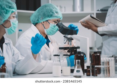 A food scientist looks at a milk sample of a product in a lab. 2 Researchers are studying and taking notes on milk. - Powered by Shutterstock