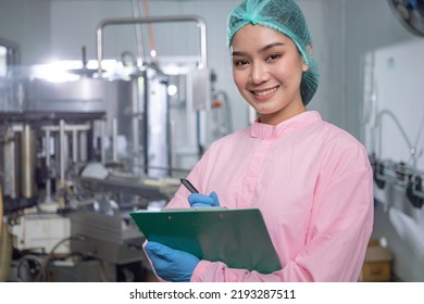 Food scientist worker checking quality of water bottle on conveyor line at industrial factory, Female worker recording data at beverages manufacturing line production - Powered by Shutterstock