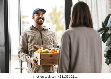 Food Shipping And People Concept - Happy Delivery Man Giving Wooden Box With Groceries To Female Customer At Home