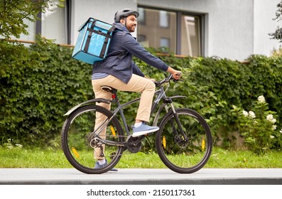 Food Shipping, Transportation And People Concept - Happy Smiling Delivery Man In Bike Helmet With Thermal Insulated Bag Riding Bicycle On City Street