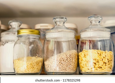 food stocks on a white kitchen shelf glass jars with cereal, pasta, corn flakes - Powered by Shutterstock