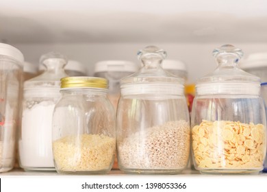 food stocks on a white kitchen shelf glass jars with cereal, pasta, corn flakes - Powered by Shutterstock