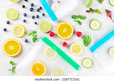 Food Storage Bags With Fruit And Vegetables, Ready For Freezing, Overhead Flat Lay Shot On A White Marble Kitchen Table. Fresh Summer Produce In Ziplock Containers