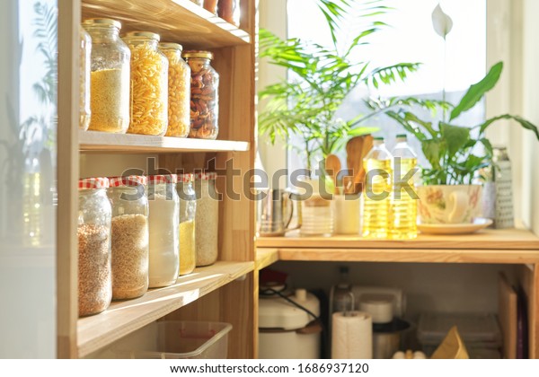 Food\
storage at home, sunflower oil on table in pantry. Pantry interior,\
wooden shelf with food cans and kitchen\
utensils