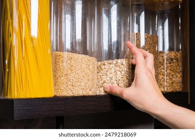 Food storage, wooden shelf in pantry with grain products in storage jars. Woman taking food for cooking - Powered by Shutterstock