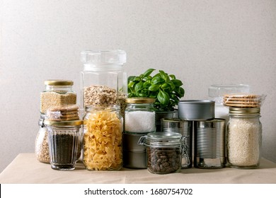 Food supplies crisis food stock for quarantine isolation period. Different glass jars with grains, pasta, cans of canned food, toilet paper, chalkboard handwritten chalk lettering Stay home and relax.