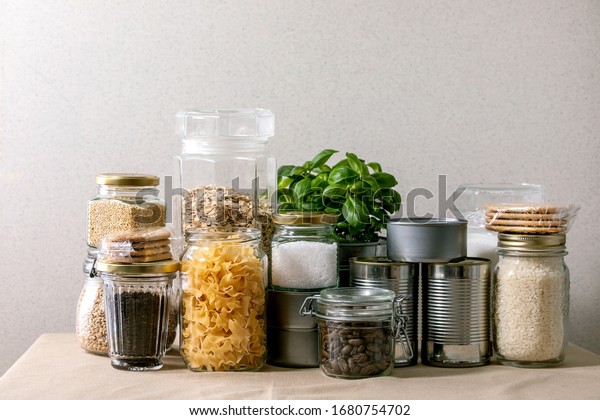 Food supplies crisis food stock for quarantine\
isolation period. Different glass jars with grains, pasta, cans of\
canned food, toilet paper, chalkboard handwritten chalk lettering\
Stay home and relax.