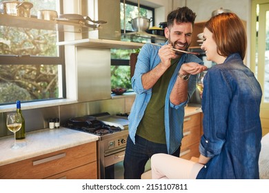 Food Tastes Better When Its Made With Love. Shot Of A Man Giving His Wife A Taste Of The Food That Hes Preparing At Home.