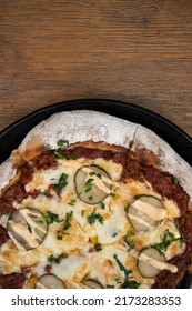 Food. Top View Of A Pizza With Minced Meat, Tomato Sauce, Grilled Cucumber, Garlic Aioli And Chives, In A Black Pizza Pan On The Wooden Table. 