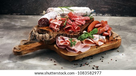 Food tray with delicious salami, ham,  fresh sausages and herbs. Meat platter with selection.