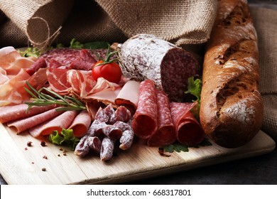 Food tray with delicious salami, pieces of sliced ham, sausage, tomatoes, salad and vegetable - Meat platter with selection - Powered by Shutterstock