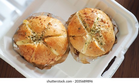 Food Trend - Korean Cream Cheese Garlic Breads Over Aluminum Foil Baking Sheets Contained In Biodegradable Leakproof Take Out Food Box On Wooden Table Background. (close Up, Top View, Selective Focus)