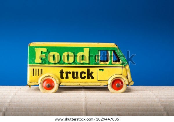 Food\
truck, vintage tin toy van on blue\
background.