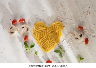 Food valentine concept. Pasta in shape of heart on light pink background. Heart mark (healthy love) made with mini tomatoes
