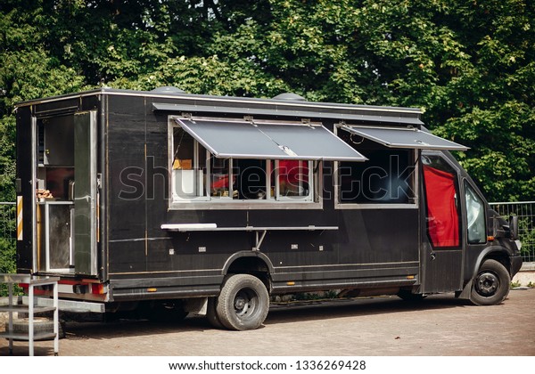 Food van truck. Stylish black mobile
food truck with burgers and asian food at street food festival.
Summer eating market in the city. Space for text,
menu