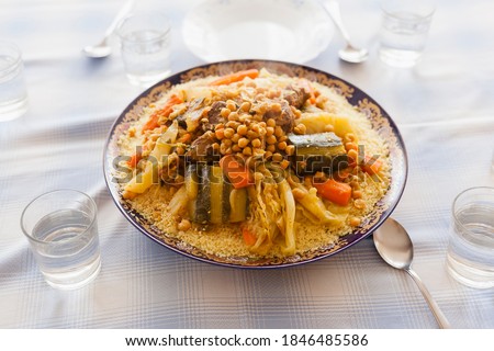 Foodie design elements friday gathering family size delicious couscous plated with stew, vegetables and beef with spoons. Moroccan gastronomy essentials for Ramadan and holidays with copy space.