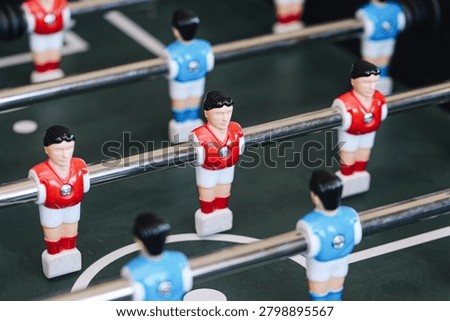 Foosball table players lined up before match. Table football game for entertainment and competition. Sports recreation background. Team strategy and leisure activity played indoors with friends.