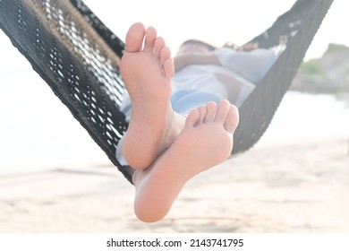 Foot Of A Beautiful Woman. She Lies In A Hammock On The Beach Of The Sea. In The Summer She Feels The Good Weather. She Is On Vacation