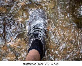 Foot With Black Socks And Grey Hiking Shoes In The River Water