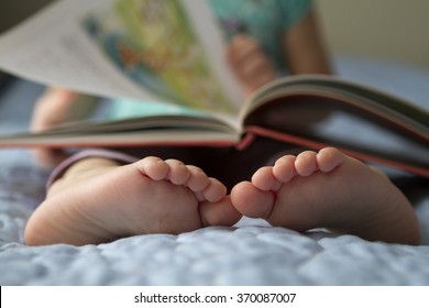 Foot Closeup. An Image Of A Toddler Reading A Book At Home