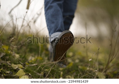 Foot detail of a woman walking on the grass, tying her shoelaces, sitting on the ground, hiking