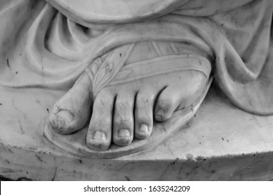 Foot. Fragment of an antique marble statue. Cracked ground in the background. Plaster limb, foot male with fingers, body part. Foots of ancient granite statue of man isolaated on white background